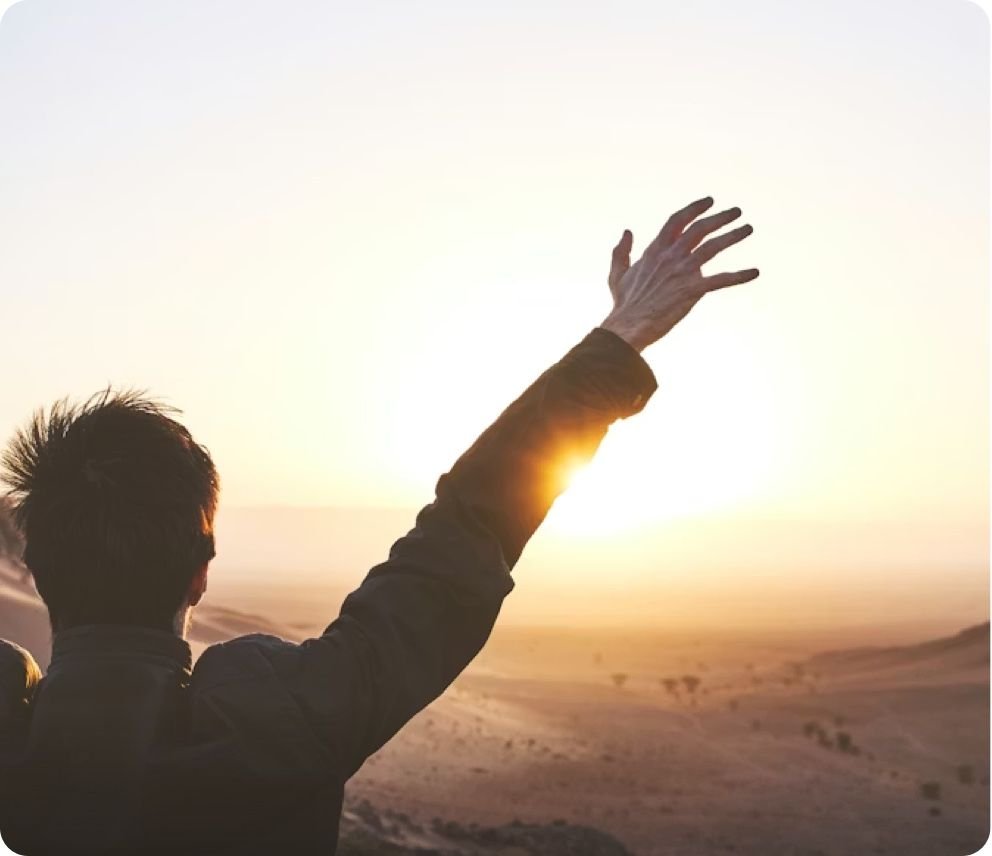 Person raising arms at sunrise, representing joy